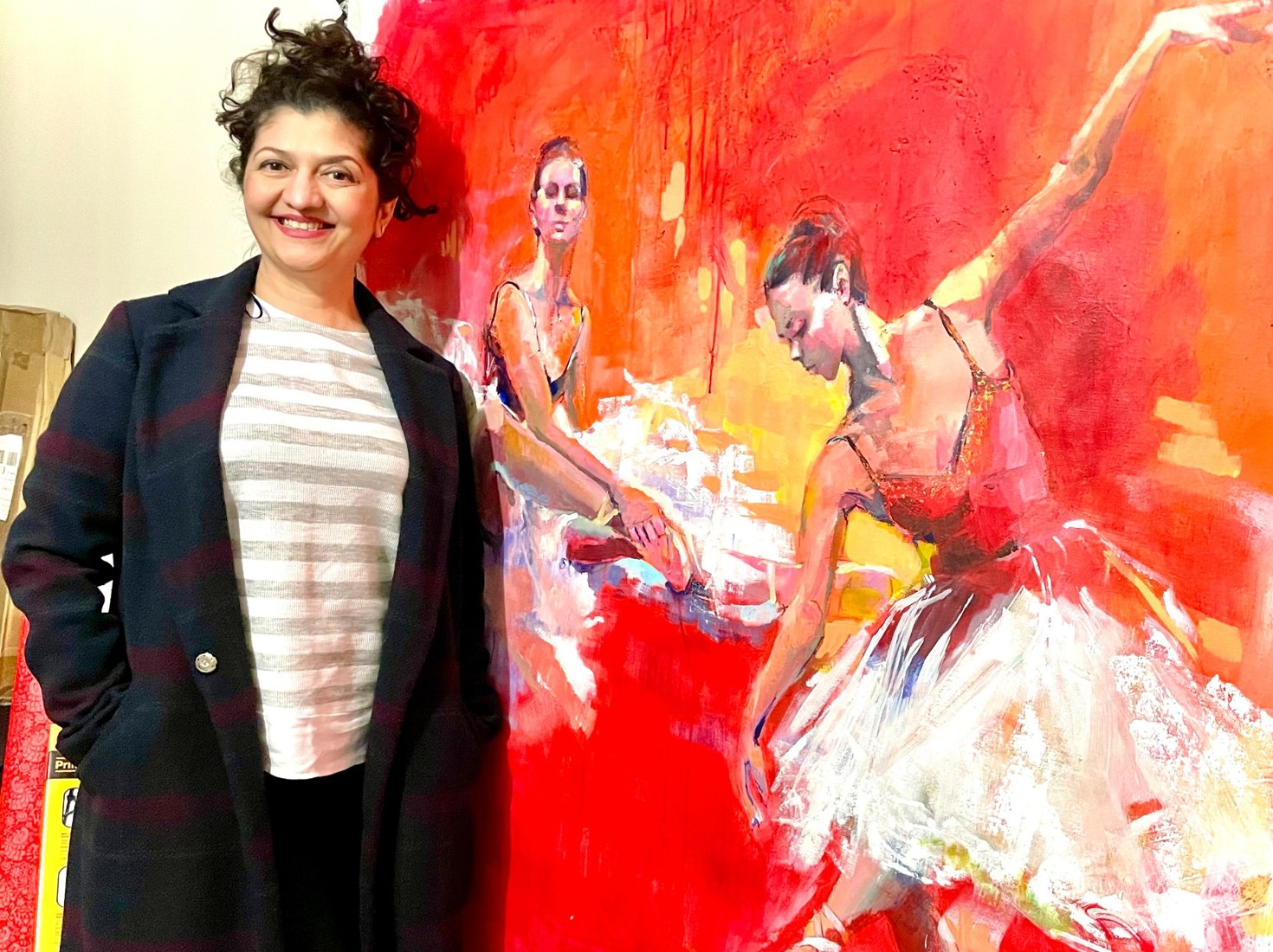 Faiqa Uppal standing beside her colourful figurative ballerina painting